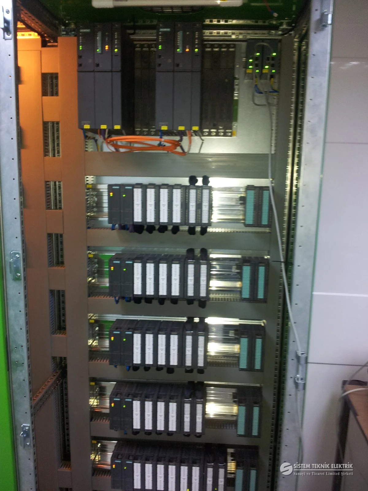 PLC ve SCADA Sistemleri — Siemens PLC modüllü pano, turuncu ışık.